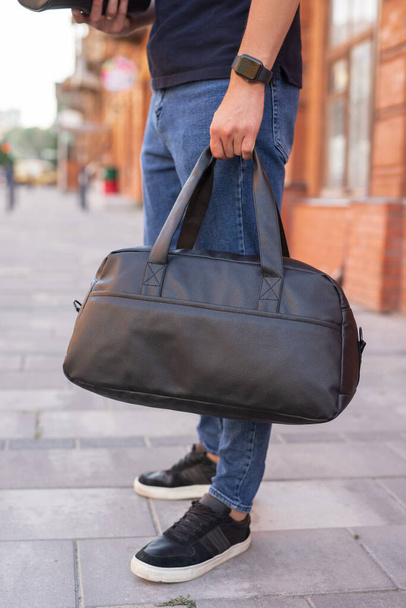 Man walking in city with black leather bag - 写真・画像
