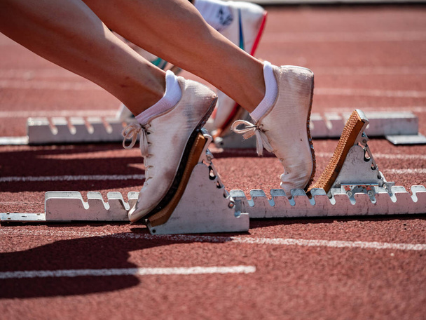 Nohy dívky běžec sprinter stopa ve startovacích blocích. Sportovní trénink na stadionu - Fotografie, Obrázek