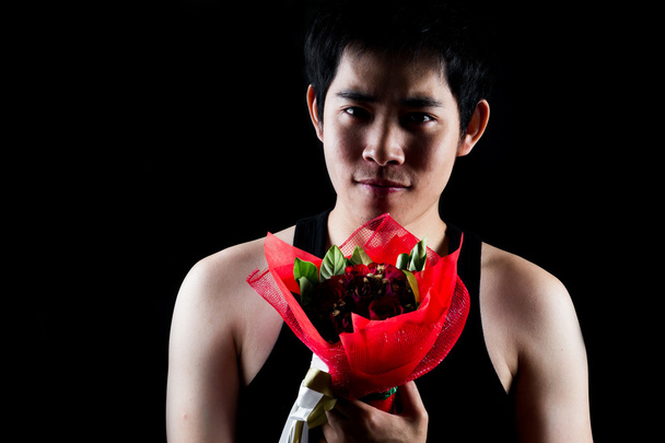 Aasialainen poika punainen kukkakimppu tumma tausta
 - Valokuva, kuva
