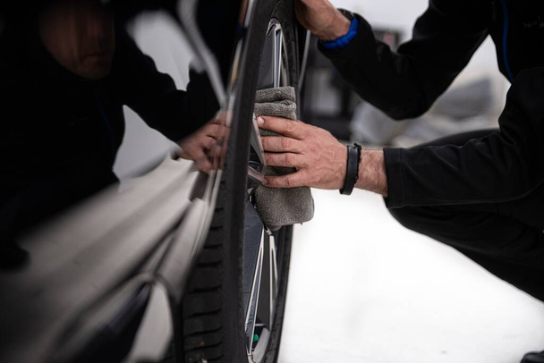 Man auto detaillering studio werknemer schoonmaken auto wiel - Foto, afbeelding