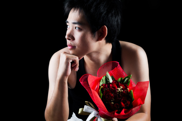 Menino asiático com buquê vermelho no fundo escuro
 - Foto, Imagem