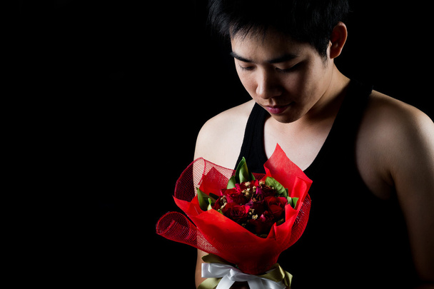 azjatycki chłopiec czerwony bukiet w ciemnym tle - Zdjęcie, obraz