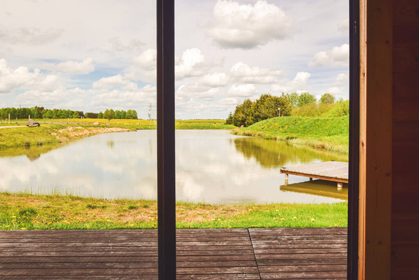 Scenic panorama calm small lake with wooden small bridge in peaceful Lithuania countryside - Фото, зображення