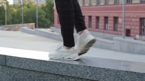 Male legs in white sneakers running on stone granite curb, closeup. Cheerful man walks alone in city, satisfied guy returns after successful date or business meeting, good mood, lightness concept  - Footage, Video