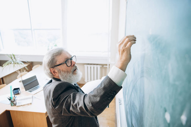 High angle view of elderly gray-headed man, professor, teacher at lecture, lesson at classroom, indoors. Concept of professional occupation, job, education - Foto, Imagen