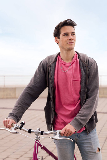 vertical portrait of a handsome young man walking with a vintage bike, concept of sustainable transportation and urban lifestyle - Fotoğraf, Görsel