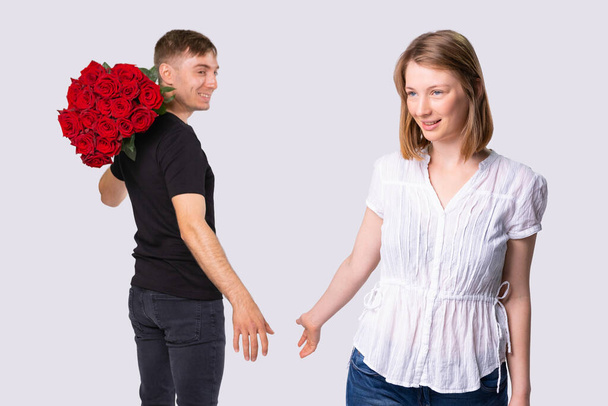 The picture of two people, courier man holding the bouquet of wonderful red roses for the pretty woman in white blouse.  - Photo, image