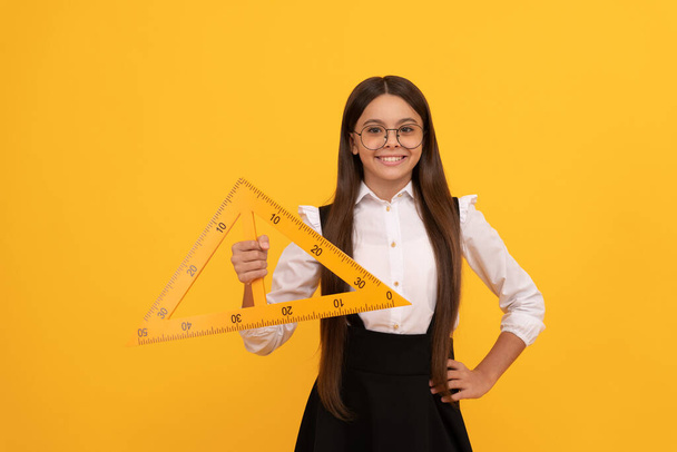 Bildung für Kinder. Mathematik. lächelnde Teenie-Mädchen halten Dreieck. Zurück zur Schule. - Foto, Bild