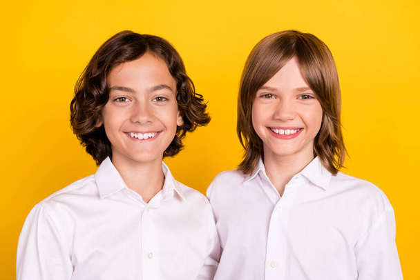 Photo of charming cute schoolchildren wear uniform smiling hugging isolated yellow color background - Fotografie, Obrázek