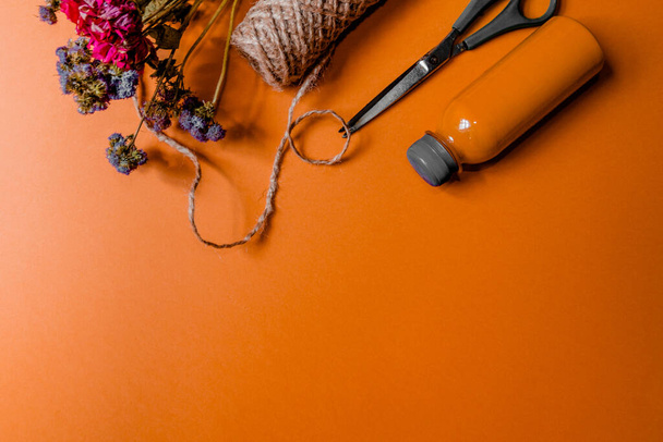 Flores, tesouras, cordéis e tinta laranja para criar uma decoração de outono ou um buquê de mentira sobre um fundo laranja. - Foto, Imagem