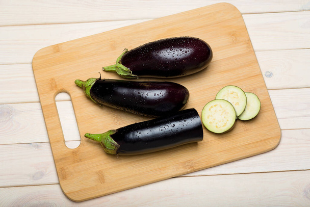 Chopped aubergines on cutting board on wooden background top view, healthy food ingredients - Foto, Imagen