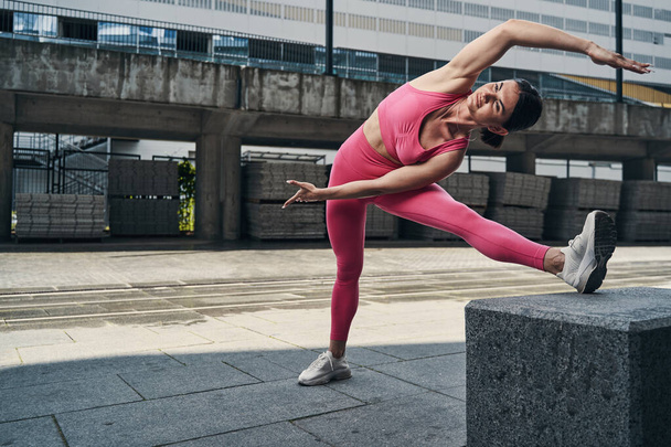Woman doing side stretches on city street - Valokuva, kuva