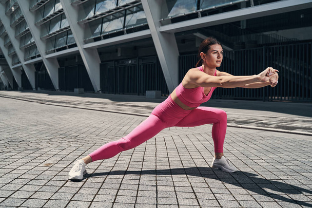 Female doing side lunge with locked hands - Photo, Image