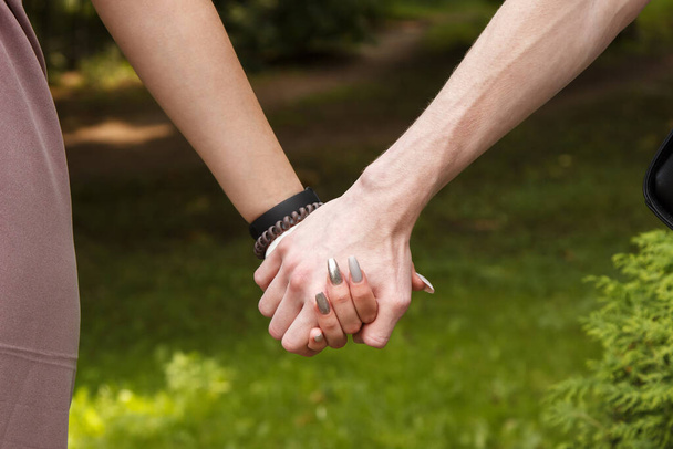 άντρας και γυναίκα κρατιούνται χέρι-χέρι. Τα χέρια κοντά. υπαίθριο την καλοκαιρινή ημέρα - Φωτογραφία, εικόνα