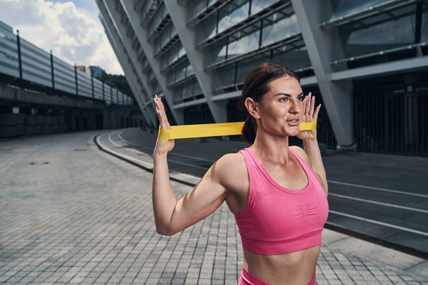 Female spreading arms with resistance band to sides - Photo, image