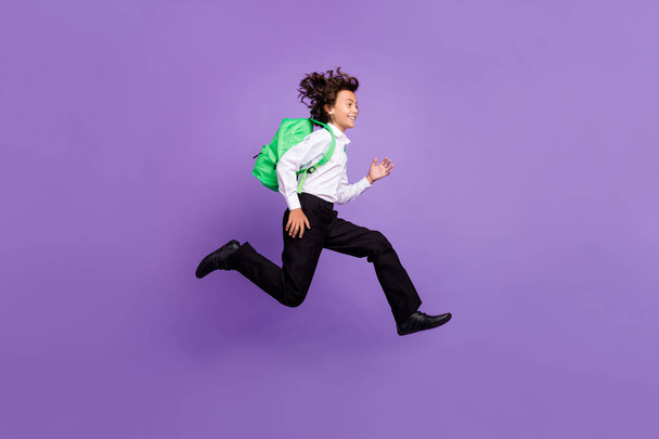 Full size photo of cool little brunet boy run wear bag shirt trousers sneakers isolated on purple background - Foto, Bild