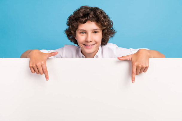 Photo of pretty charming schoolboy wear white shirt pointing fingers billboard empty space isolated blue color background - Foto, afbeelding