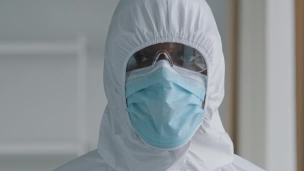Portrait of african man doctor scientist medical worker wears protective clothing hood face mask and glasses looks at camera shows covid pcr test tube with cotton swab equipment for diagnostic covid19 - Metraje, vídeo