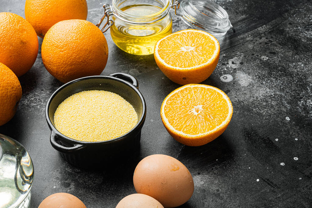 Orange Polentakuchen-Zutaten, mit Eiern und Honig-Set, auf schwarzem dunklem Steintischhintergrund - Foto, Bild