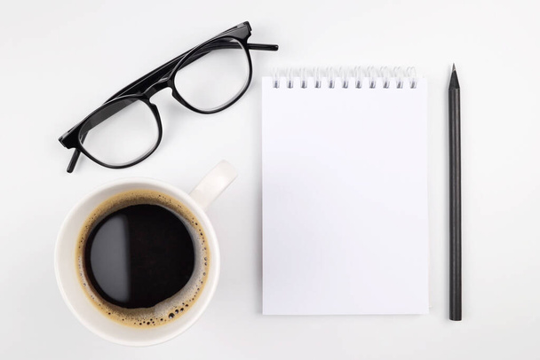 A notebook,a cup of coffee, a pencil,glasses on a white background.Things for businessmen,teachers, artists.The concept of writing in a notebook in the first person, planning, making a to-do list. - Foto, Imagem