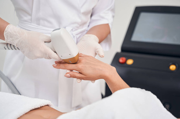Woman doing laser epilation on fingers in clinic - Photo, Image