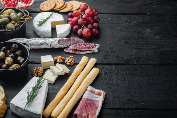 チーズと肉の前菜セットの盛り合わせ、テキスト用のコピースペース付きブラックウッドテーブルの上 - 写真・画像