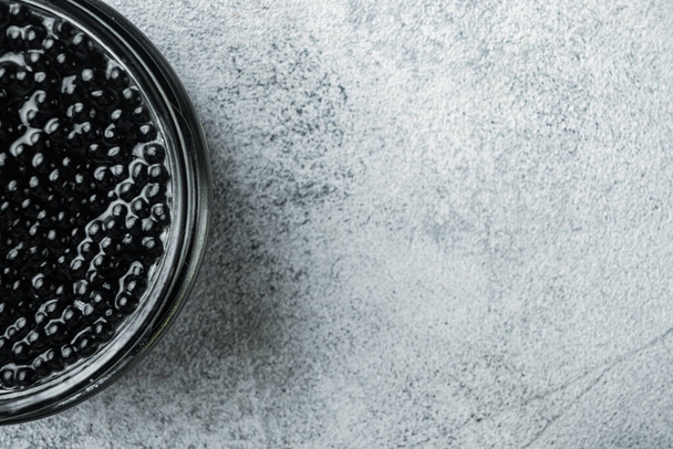 Schwarzer Stör-Kaviar, auf grauem Hintergrund, von oben flach liegend mit Kopierraum für Text - Foto, Bild