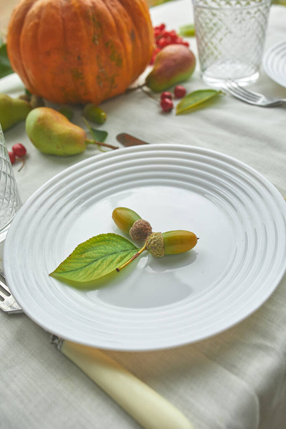 Thanksgiving Day or Halloween dinner table place setting decorative with pumpkin, acorns, pears leaves on white tablecloth background, view from above, top view, flat lay - Foto, Imagen