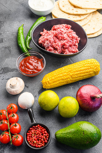 Ingredientes para carne de vacuno tacos mexicanos, tortillas de maíz, chile, aguacate, carne sobre fondo gris texturizado, vista lateral - Foto, imagen