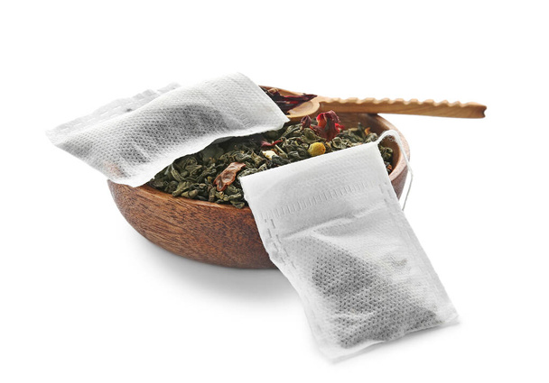 Tea bags and bowl with dry leaves on white background - Photo, Image