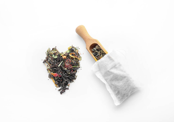 Sachet de thé et cuillère avec des feuilles sèches sur fond blanc - Photo, image