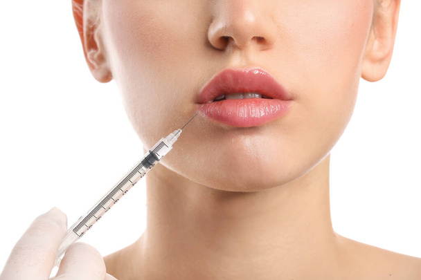 Young woman receiving filler injection in lips against white background, closeup - Φωτογραφία, εικόνα
