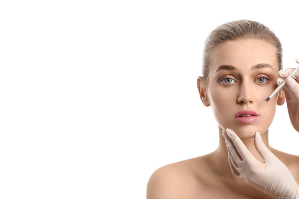молодая женщина получает инъекции наполнителя в губы на белом фоне - Фото, изображение