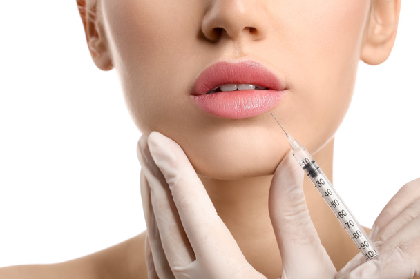 Young woman receiving filler injection in lips against white background, closeup - Photo, Image