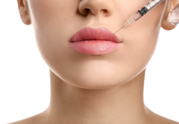 Young woman receiving filler injection in lips against white background, closeup - Φωτογραφία, εικόνα