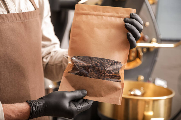 焙煎したコーヒー豆の袋を持つシニア男,クローズアップ - 写真・画像