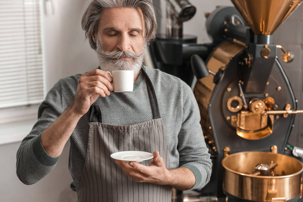 Senior mit Tasse Heißgetränk in der Nähe moderner Kaffeeröster - Foto, Bild