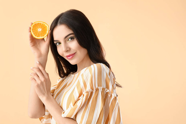 Красива молода жінка з апельсином на кольоровому фоні
 - Фото, зображення