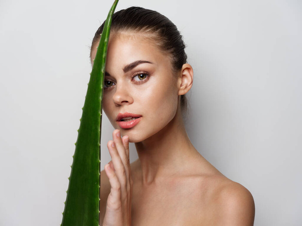 Frau mit nackten Schultern und Aloe-Blatt im Vordergrund Kosmetologie - Foto, Bild