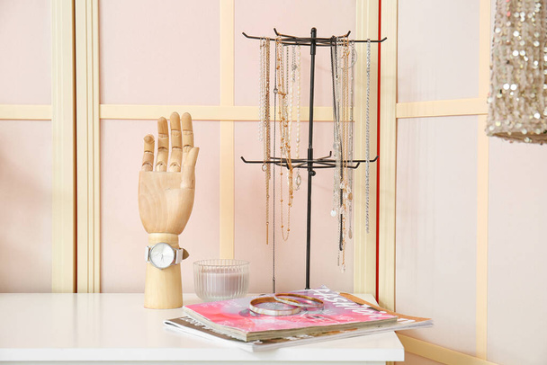 Mão de madeira com acessórios e revistas na prateleira perto da tela dobrável - Foto, Imagem