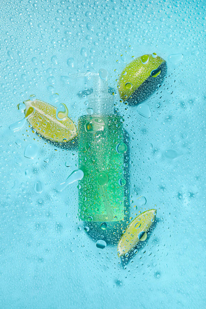 Bottle of cosmetic product and lime in water on color background - Fotoğraf, Görsel
