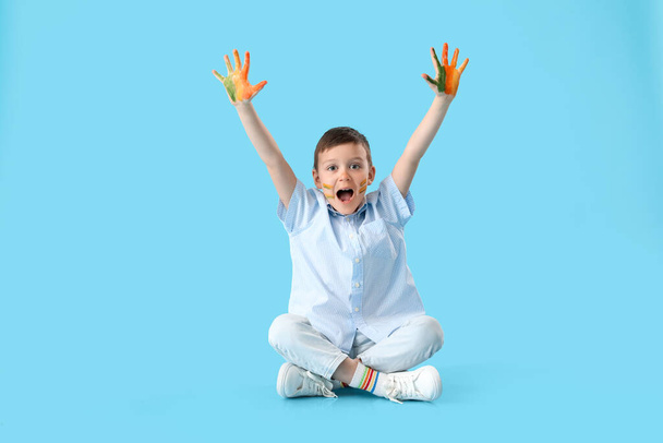 Симпатичный маленький мальчик с руками в краске на цветном фоне - Фото, изображение
