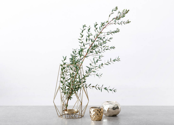 Vase with eucalyptus branches and candles on table against white background - Photo, image
