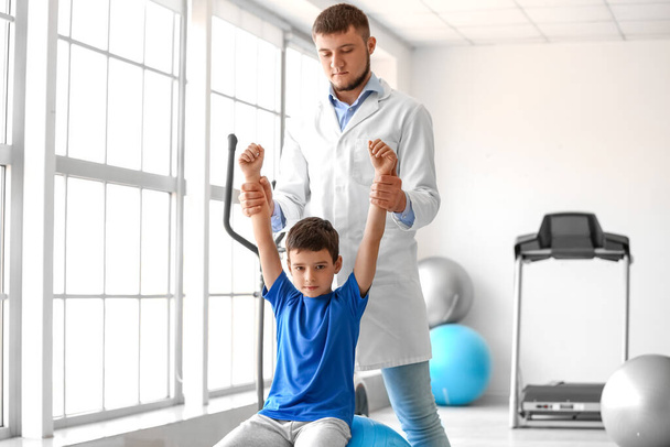 Fysiotherapeut werkt met jongen in revalidatiecentrum - Foto, afbeelding