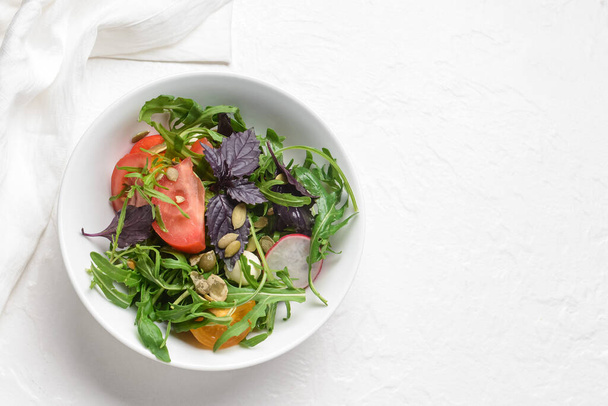 Bol avec salade fraîche savoureuse sur fond clair - Photo, image