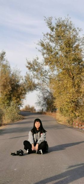 young woman sitting on the road and looking at the camera - Foto, Imagen