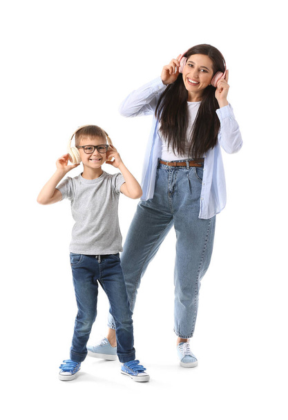 Young woman and her little son dancing and listening to music on white background - Photo, Image