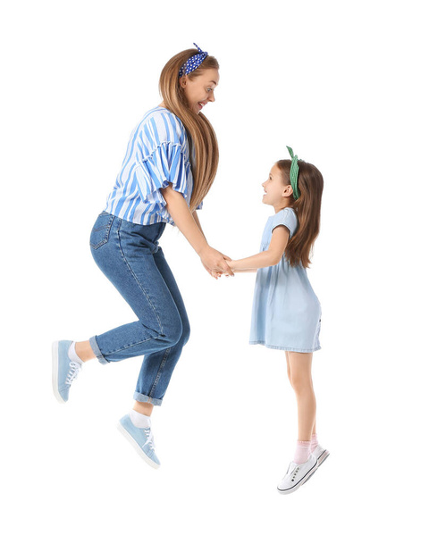 Стрибає молода жінка і її маленька донька на білому тлі
 - Фото, зображення