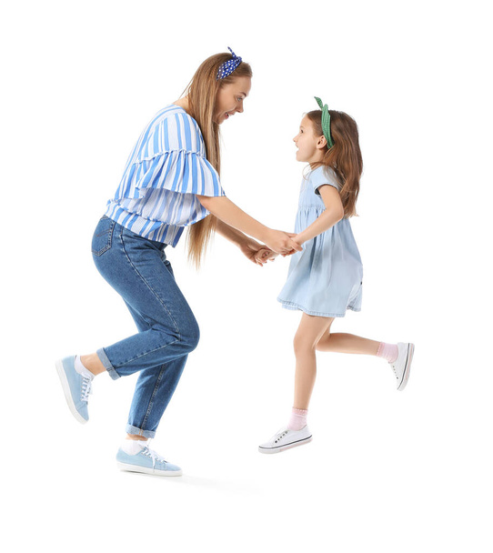 Jumping junge Frau und ihre kleine Tochter auf weißem Hintergrund - Foto, Bild