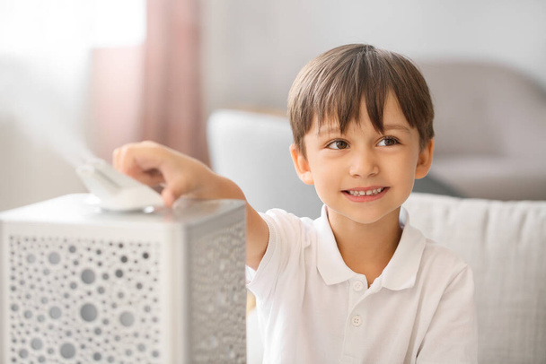 Маленький мальчик с современным увлажнителем воздуха дома - Фото, изображение